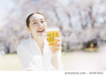 Middle woman drinking beer in the park during cherry blossom viewing 64467681