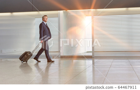 Mature businessman walking with his suitcase in Mature businessman walking with his suitcase in 64467911