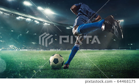 Football or soccer player in action on stadium with flashlights, kicking ball for winning goal, wide angle. Action, competition in motion 64468175