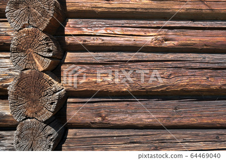 Wooden background. Wall from old dilapidated longitudinal and transverse logs. 64469040