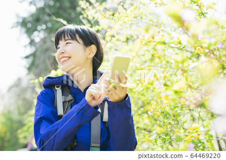 A woman taking a plant with a smartphone while hiking 64469220