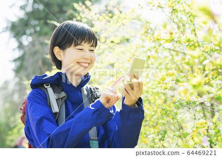 A woman taking a plant with a smartphone while hiking 64469221