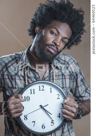 afroamerikaner in a checkered shirt holds the large white clock 64469525