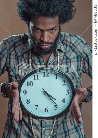 afroamerikaner in a checkered shirt holds the large white clock afroamerikaner in a checkered shirt holds the large white clock 64469539