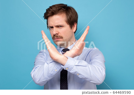 Serious young man in shirt showing stop sign Serious young man in shirt showing stop sign 64469590