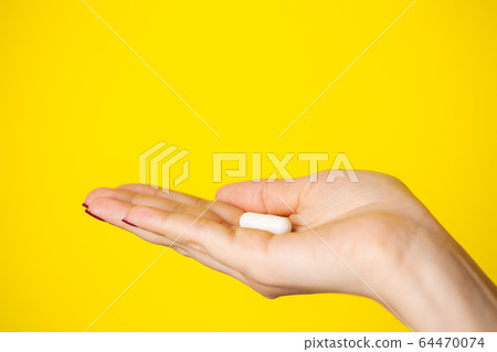 Woman holds white pill in her hand for weight loss 64470074
