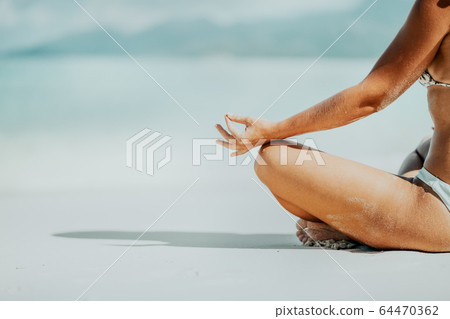 Crop of female hands and legs meditating activity on the beach Crop of female hands and legs meditating activity on the beach 64470362