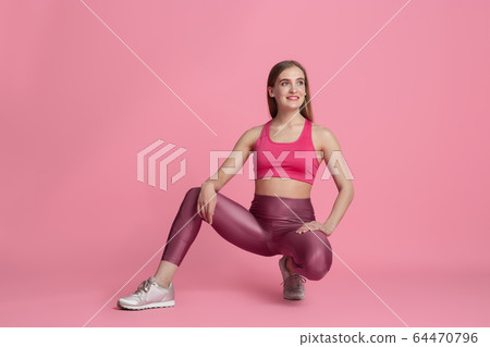 Beautiful young female athlete practicing on pink studio background, monochrome portrait Beautiful young female athlete practicing on pink studio background, monochrome portrait 64470796