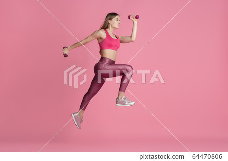 Beautiful young female athlete practicing on pink studio background, monochrome portrait 64470806