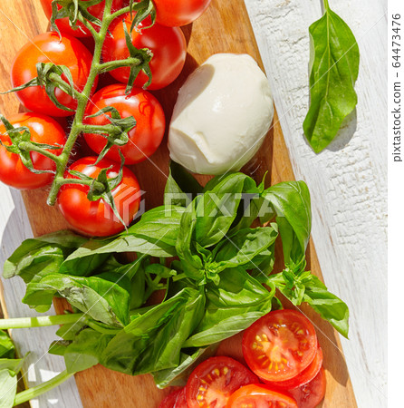 mozzarella, organic cherry tomatoes and fresh basil on a rustic wooden background mozzarella, organic cherry tomatoes and fresh basil on a rustic wooden background 64473476