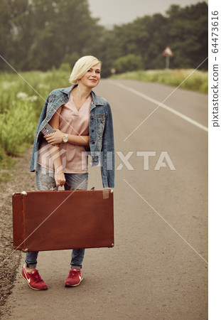 Traveler girl with a suitcase on the road. Concept of travel, vacation, solo-female tourism, travel, adventure. Traveler girl with a suitcase on the road. Concept of travel, vacation, solo-female tourism, travel, adventure. 64473616