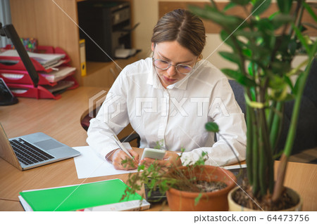 Caucasian entrepreneur, businesswoman, manager working concentrated in office Caucasian entrepreneur, businesswoman, manager working concentrated in office 64473756