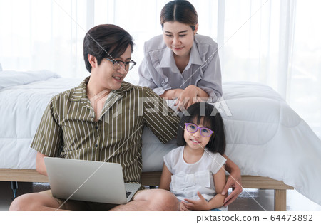 Parents and children are playing in the bedroom 64473892