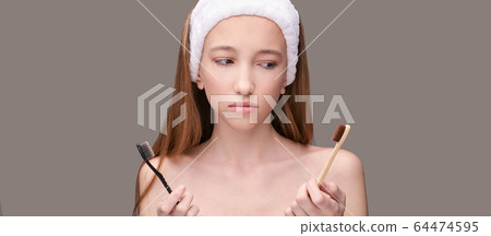 Girl hold toothbrush. Choice bamboo and plastic. Oral home routine Girl hold toothbrush. Choice bamboo and plastic. Oral home routine 64474595