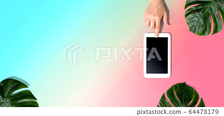 Person using a tablet computer with tropical leaves Person using a tablet computer with tropical leaves 64478179