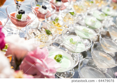 Glass sweets lined up outdoors, the image of a party buffet 64479078