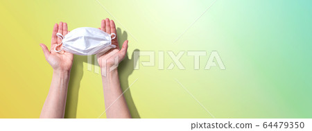 Person holding a white surgical mask overhead view 64479350