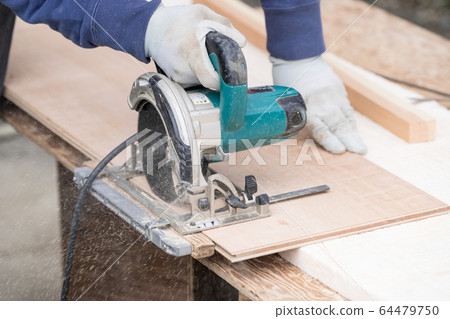 Close-up of the hand of the craftsman who is cutting flooring with electric circular saw 64479750