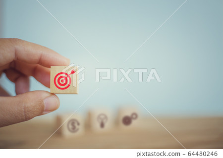 Hand chooses wooden cube block symbol and goal target icon. Tactics of advertising targeting. advertise campaigns. Goal Achievement and Purposefulness. 64480246