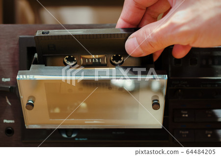 Male hand inserting tape into cassette deck Male hand inserting tape into cassette deck 64484205