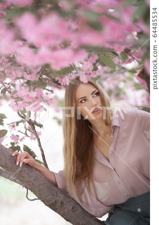 Woman at Blossoming Sakura Tree on Nature 64485534