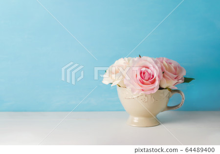 Artificial pink rose flowers in vintage cup on 64489400
