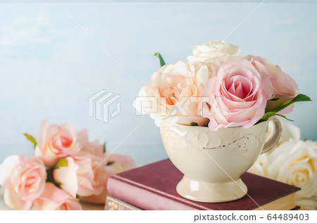 Artificial pink rose flowers in vintage cup with Artificial pink rose flowers in vintage cup with 64489403