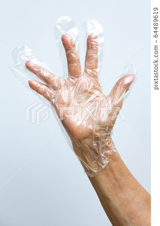 Senior woman's hand wearing disposable protective plastic glove on grey background, Close up shot, Prevention from covid19, Coronavirus, Bacteria, Healthcare 64489619