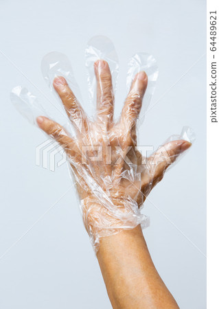 Senior woman's hand wearing disposable protective plastic glove on grey background, Close up shot, Prevention from covid19, Coronavirus, Bacteria, Healthcare Senior woman's hand wearing disposable protective plastic glove on grey background, Close up shot, Prevention from covid19, Coronavirus, Bacteria, Healthcare 64489621