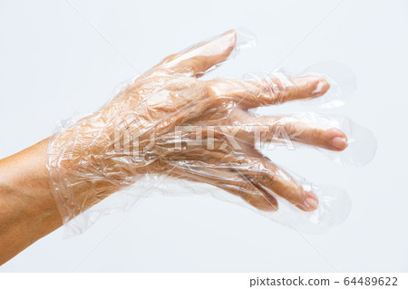 Senior woman's hand wearing disposable protective plastic glove on grey background, Close up shot, Prevention from covid19, Coronavirus, Bacteria, Healthcare 64489622