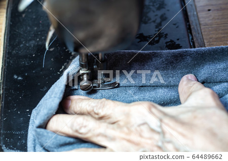 Senior woman's stitching grey fabric on vintage sewing machine, Thread, Needle, Close up shot, Selective focus, Sewing process, Female's hobby. Tailor concept 64489662