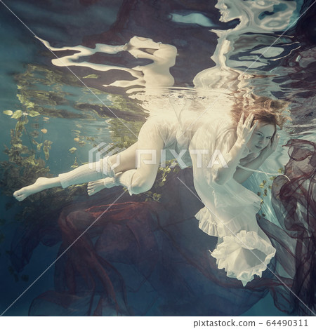 Portrait of a girl floating underwater Portrait of a girl floating underwater 64490311