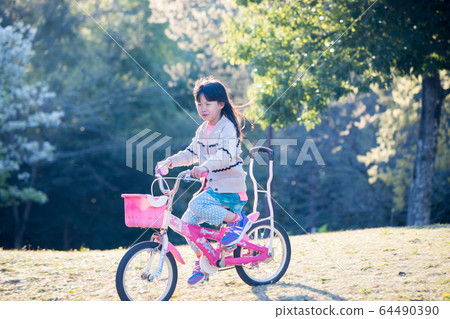 A child riding a bicycle in the spring park A child riding a bicycle in the spring park 64490390