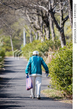 高級的女人在春天公園散步 64490392