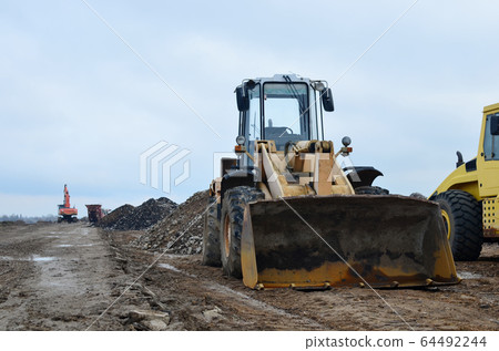 Front-end loader working on construction site Front-end loader working on construction site 64492244