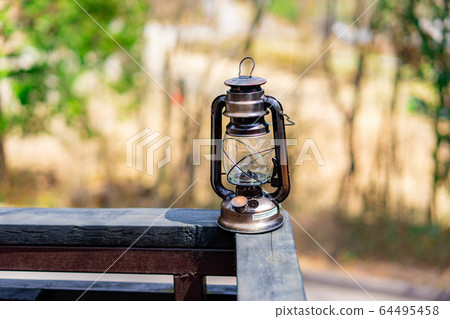 A Old Rustic Oil Lantern On A Wood Block At A Camping Site Stock