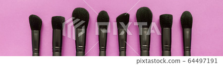 Flat lay of black makeup brushes collection on pink background 64497191