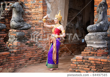 Portrait of an Asian Women in Thai Traditional dancer Clothes are Standing Against Ancient buddha statue. Ayuttaya Historical Park, Thailand Asia. Portrait of an Asian Women in Thai Traditional dancer Clothes are Standing Against Ancient buddha statue. Ayuttaya Historical Park, Thailand Asia. 64497585