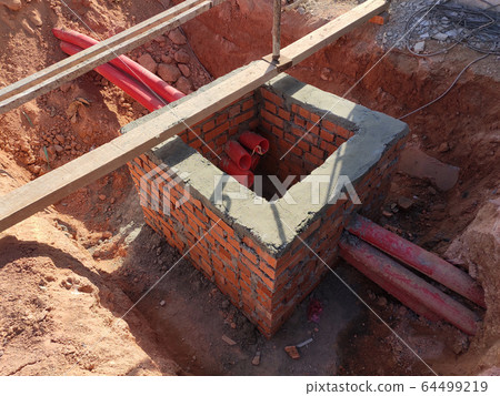 Utility services manhole under construction at the construction site. In-situ construction by workers based on infrastructure engineer design. 64499219