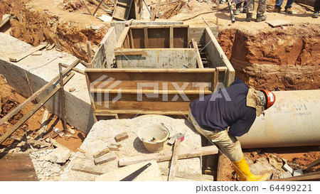Utility services manhole under construction at the construction site. In-situ construction by workers based on infrastructure engineer design. 64499221