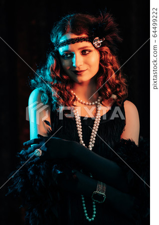 Portrait of old-fashioned red haired woman dressed in style of Great Gatsby era flirting and posing 64499222