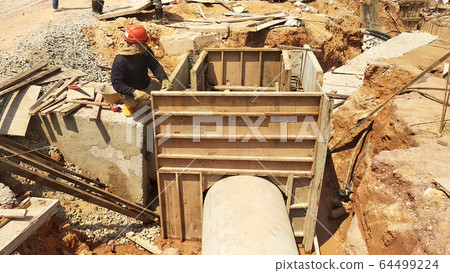 Utility services manhole under construction at the construction site. In-situ construction by workers based on infrastructure engineer design. Utility services manhole under construction at the construction site. In-situ construction by workers based on infrastructure engineer design. 64499224