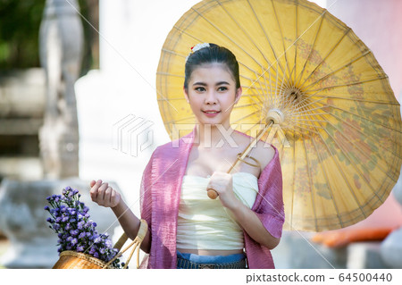Portrait of an Asian Women in Thai Lanna and Shan Traditional Clothes are Standing and hold umbrella Against Thailand Temple Portrait of an Asian Women in Thai Lanna and Shan Traditional Clothes are Standing and hold umbrella Against Thailand Temple 64500440