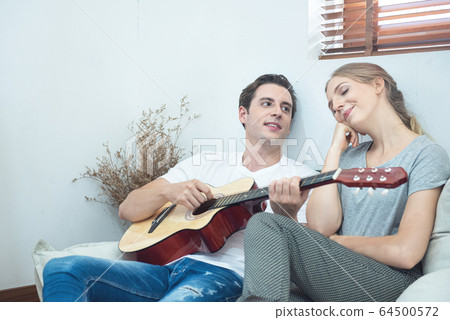 Happy young handsome caucasian man play guitar and Happy young handsome caucasian man play guitar and 64500572