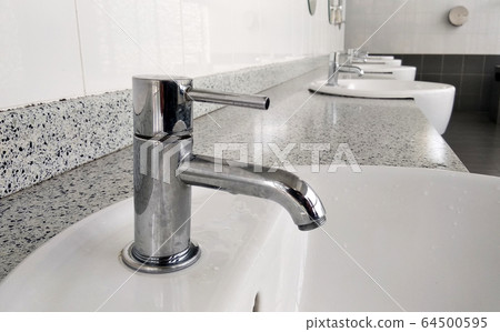 Public toilet counter top complete with basins, water taps, and face mirror. Arranged in one line for public use. Public toilet counter top complete with basins, water taps, and face mirror. Arranged in one line for public use. 64500595