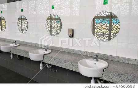 Public toilet counter top complete with basins, water taps, and face mirror. Arranged in one line for public use. Public toilet counter top complete with basins, water taps, and face mirror. Arranged in one line for public use. 64500598