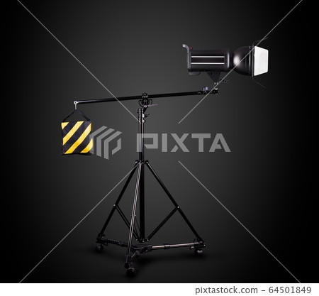 Photography studio flash on a lighting stand isolated on black background. 64501849