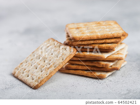 Stack of square organic crispy and salty crackers Stack of square organic crispy and salty crackers 64502421