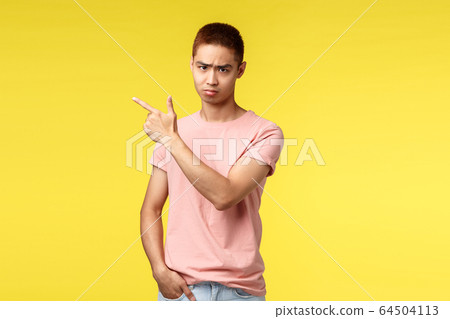 People, different emotions and lifestyle concept. Portrait of gloomy, sad and disappointed asian male pointing finger upper left corner, look angry from under forehead, feel displeased and envy People, different emotions and lifestyle concept. Portrait of gloomy, sad and disappointed asian male pointing finger upper left corner, look angry from under forehead, feel displeased and envy 64504113