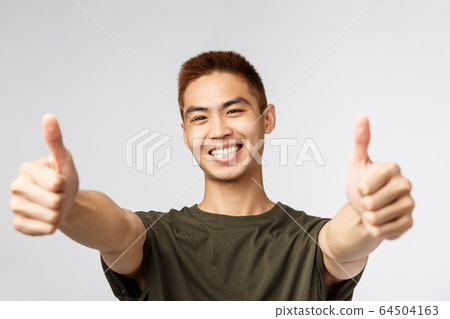 People, different expressions and lifestyle concept. Close-up portrait of enthusiastic japanese guy saying yes, approve product, give recommendation and guarantee best quality, thumbs-up 64504163